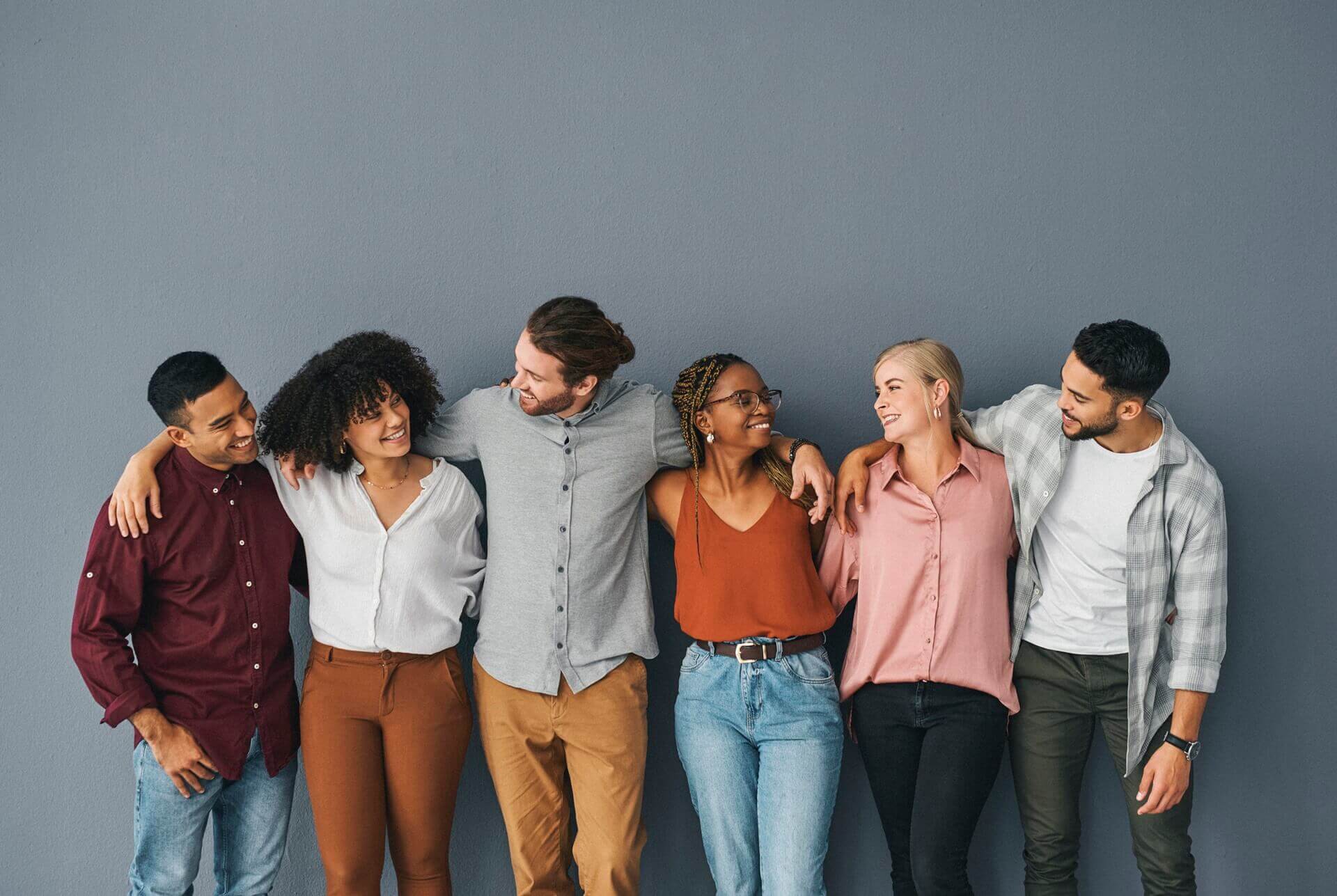 Young and diverse group of business people standing together against a grey background