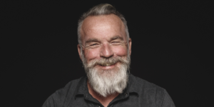 A portrait of an old man smiling against a black background