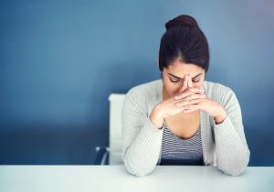 Shot of an overwhelmed young businesswoman holding her head in her hands while sitting at her desk and wrestling with rejection