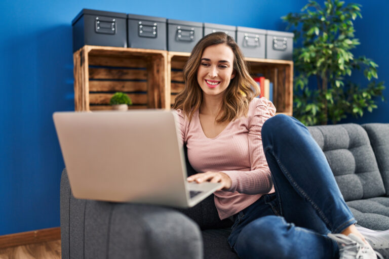 Young woman using laptop sitting on sofa at home